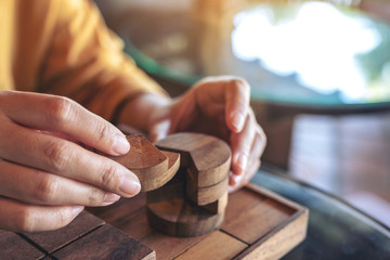 Closeup image of people playing and building round wooden puzzle game