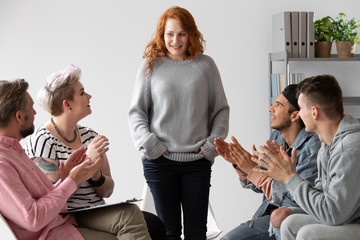 Smiling girl in the middle of young people. Teenagers clapping hands during meeting