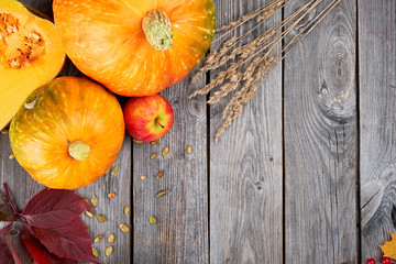 Autumn harvest Thanksgiving pumpkins, apples, wheat ears and fallen leaves on wooden background. Seasonal Fall Food