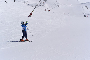 A boy in a blue  ski jumpsuit skiing from the snowy mountains of the Sierra Nevada