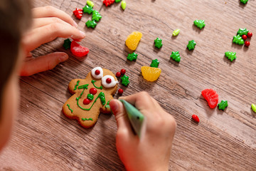 child decorates gingerbread cookie. the gingerbread man on a wooden table. the concept of...