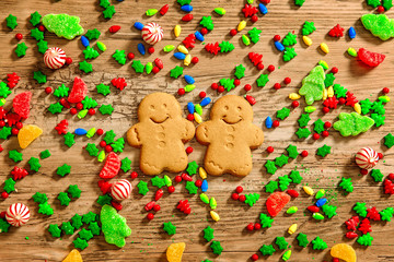 background of Christmas sweets on a wooden table. couple of gingerbread cookies among Christmas candies