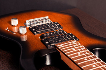 Electric guitar with six strings on a wooden table. Close-up fragment of the body, signature stamp.