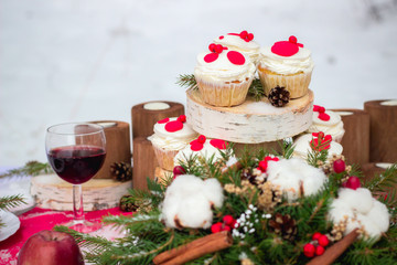 Fototapeta na wymiar Festive table setting for Christmas for two with cupcakes, red wine