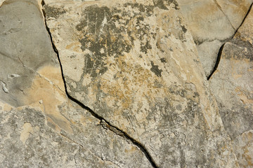 Mountain stone with a natural texture as a design concept. Cracks created by nature on the surface of the stone with a natural color scheme, create a natural textured background. Texture for design .