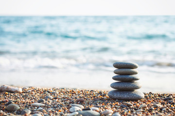 Fototapeta na wymiar The zen gardens stones on a beach sand. Water waves texture. Spa stones balance pyramid. Place for text.