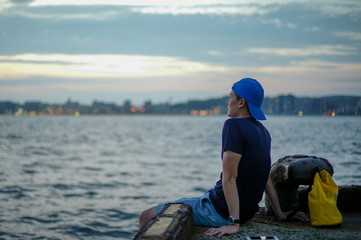 Portrait Asian man sitting on the port and looking out to the sea