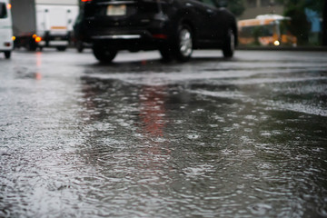 Heavy rain falls on asphalt with blurry cars (focus on road surface)