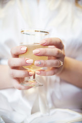 Bride's hand with a wedding ring holding a glass of champagne with bubbles.