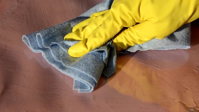 Close up of hands in rubber protective yellow gloves cleaning the white surface with a rag. Home, housekeeping concept