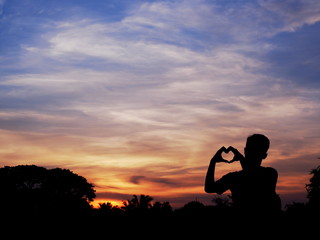 Silhouette of young man forming hand to heart shape, Sunrise scene, Silhouette photography.