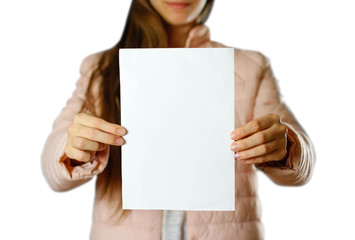 A woman in a warm winter jacket holding a white leaflet. Blank paper. Close up. Isolated on white background