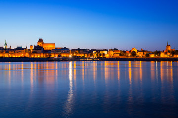 Obraz premium Old town of Torun at night reflected in Vistula river, Poland