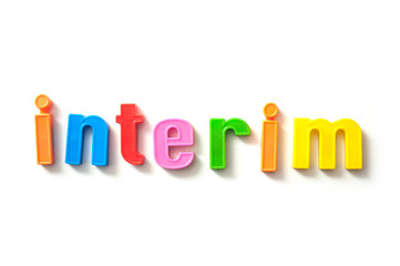 closeup of colorful plastic letters on white background - Interim