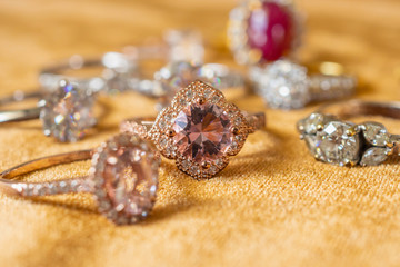 Fototapeta na wymiar Jewelry pink diamond rings on golden fabric background close up
