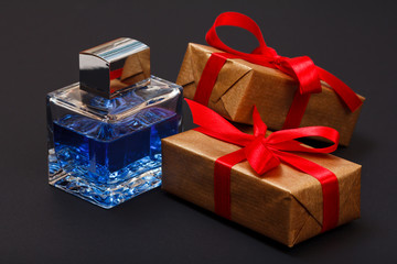 Gift boxes tied with ribbon and bottle of perfume on black background