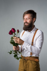 A man with a beard holds with a bouquet of roses