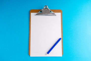 Clipboard and pencil on blue background with selective focus and crop fragment