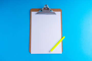 Clipboard and pencil on blue background with selective focus and crop fragment