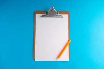 Clipboard and pencil on blue background with selective focus and crop fragment