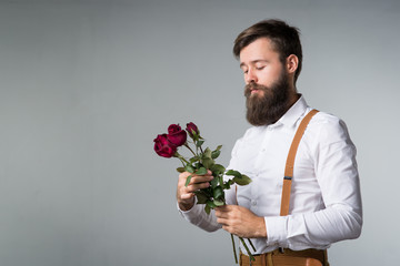 A man with a beard holds with a bouquet of roses