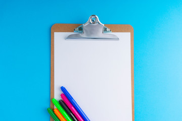 Clipboard and pencil on blue background with selective focus and crop fragment