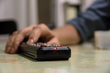Fototapeta premium Turning on the TV and switching channels with a female hand remote control