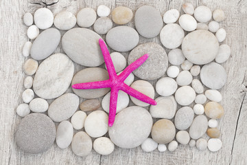 Flatlay image with pink starfish on a smooth pebble surface