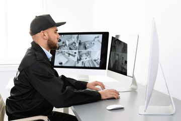 Male security guard monitoring home cameras indoors