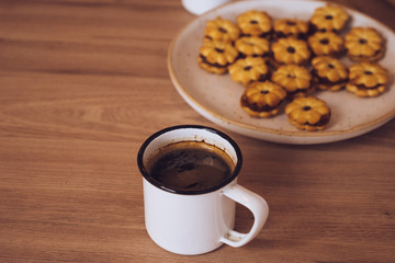 Top view of a cup of coffee and a plate of snacks on a wooden table