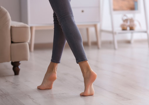 Young woman walking barefoot at home, closeup. Heating concept