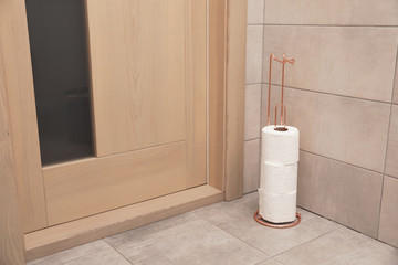 Fototapeta na wymiar Holder with toilet paper rolls on floor indoors