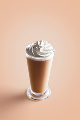 Large cappuccino coffee in transparent mug with cream on a colorful background