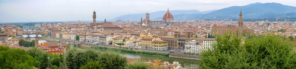 Panorama of Florence, Italy, showing the skyline with churches, cathedrals and palaces, the river San Lorenzo and the bridge on a cloudy summer day, seen from high above