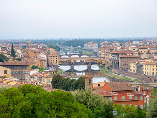 Fototapeta na wymiar Panorama of Florence, Italy, showing the skyline with churches, cathedrals and palaces, the river San Lorenzo and the bridge on a cloudy summer day, seen from high above