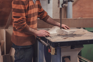 Carpenter cutting wood on tape saw