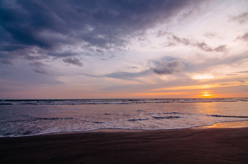 Obraz premium Sunset Sky with Dark Clouds Over Ocean Sand Beach