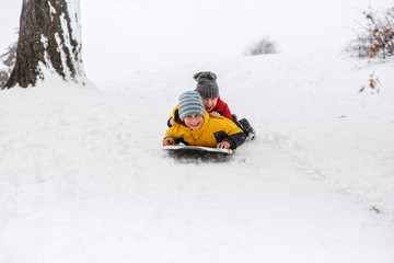 Fototapeta na wymiar cheerful children slide down hills on sled. boys having fun in the snow