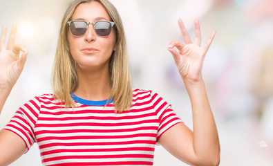 Young beautiful woman wearing sunglasses over isolated background relax and smiling with eyes closed doing meditation gesture with fingers. Yoga concept.