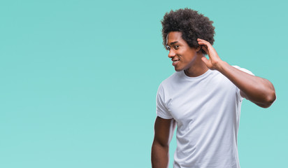 Afro american man over isolated background smiling with hand over ear listening an hearing to rumor or gossip. Deafness concept.