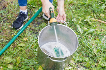 man's hands wash dishes with water hose