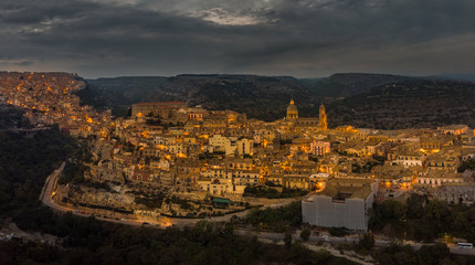 Fototapeta na wymiar Aerial panorama of Ragusa Ibla and Ragusa Superiore or Upper town - a part of a UNESCO World Heritage Site. Night lights of the city of Ragusa, Sicily. Cathedral of San Giorgio built in baroque style