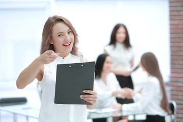 confident young business woman with clipboard on the background of business team