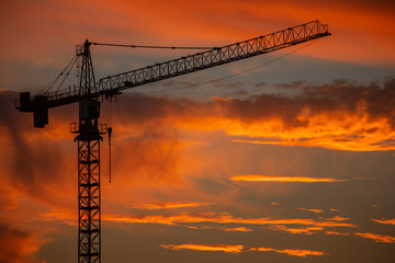 Silhouette of construction crane in front of sunset