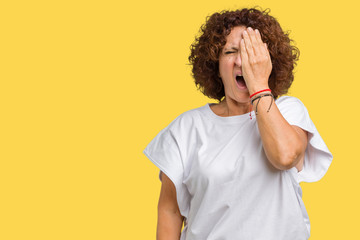 Beautiful middle ager senior woman wearing white t-shirt over isolated background Yawning tired covering half face, eye and mouth with hand. Face hurts in pain.