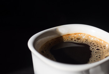 Hot black coffee in white cup on black background