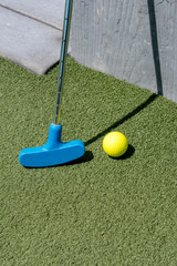 Yellow Golf ball and blue stick on green lawn