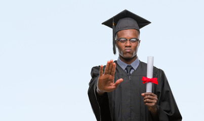 Young graduated african american man holding degree over isolated background with open hand doing stop sign with serious and confident expression, defense gesture