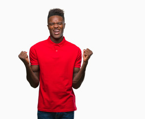 Fototapeta premium Young african american man over isolated background celebrating surprised and amazed for success with arms raised and open eyes. Winner concept.