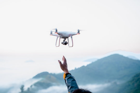 Man using drone to monitor take a picture of fog and mountains in the morning.Hand rising to sky with drone flying over mountains with fog background.